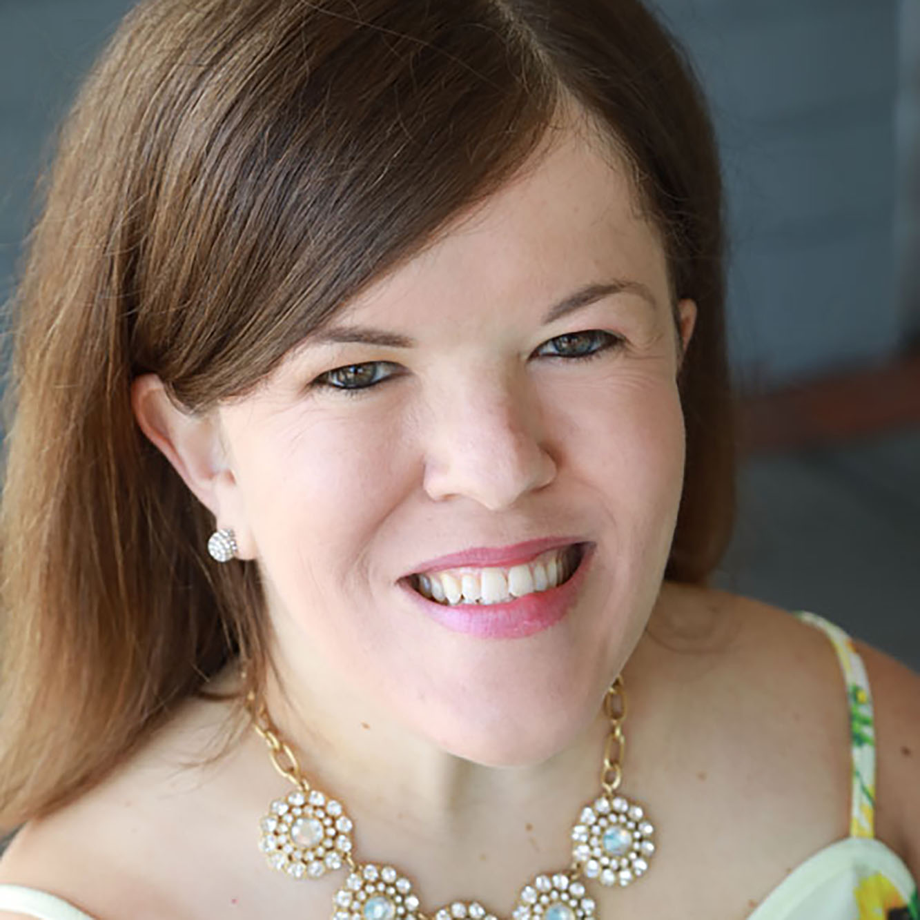 Woman with light brown hair smiling with red lipstick.