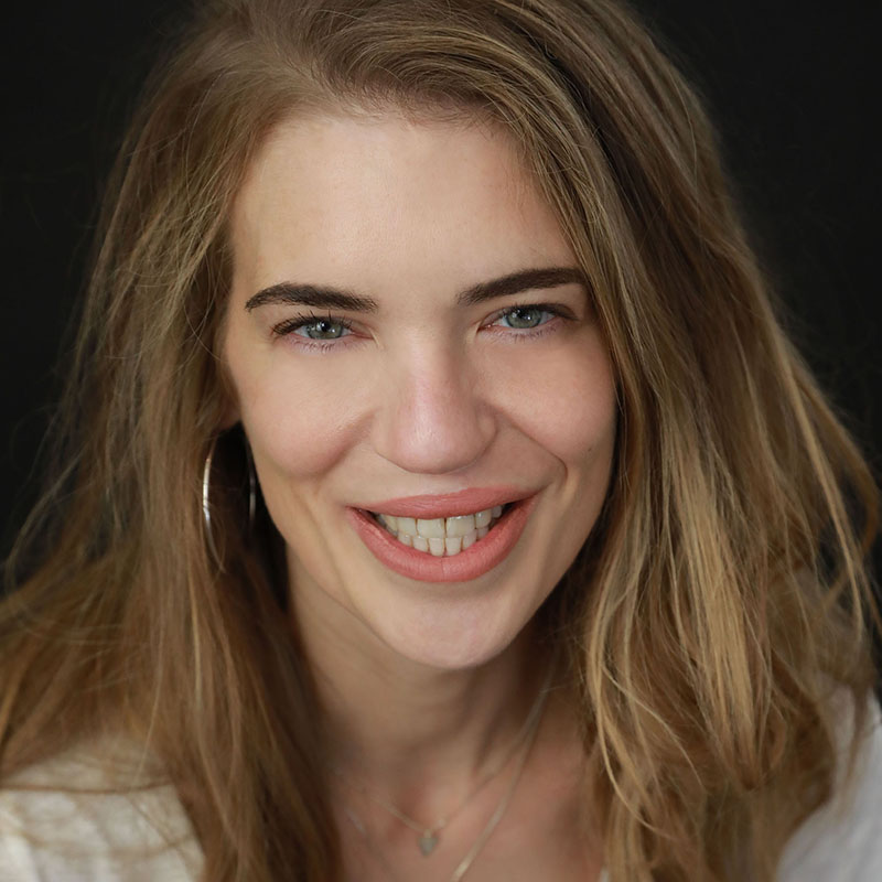 Light-skinned woman with long blond hair and hoop earring, smiling.