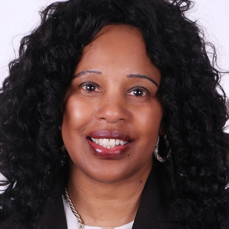 Medium-skinned woman with dark curly hair, smiling.