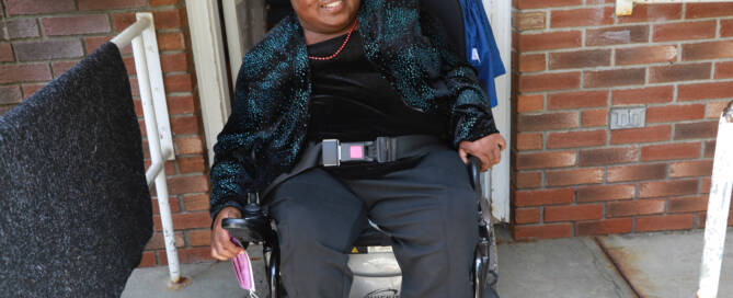 Woman in wheelchair in dark blue jacket, smiling