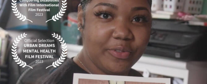 Image Description: Young woman with beautiful smooth brown skin, long eyelashes, manicured fingernails, wearing a black top, holding up a water color self portrait in green blouse. The top of the image reads Faces Redefining The Art Of Medical Education. 2 Film Festival Laurels are overlaid image on left “Official Selection Conquering Disabilities with Film International Film Festival 2023″ and “Official Selection of Urban Dreams Mental Health Film Festival 2023”. At bottom of images, Another Way To Love Yourself in large white letters, with smaller text below, A Short Film by Rick Guidotti, Victor Ilyukhin and Olga Lvoff Produced by Rick Guidotti and Positive Exposure