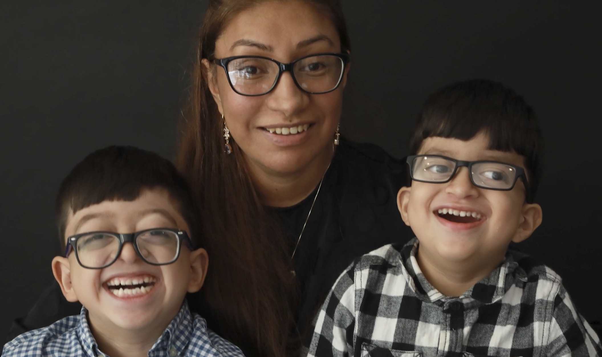 Mom and 2 young boys, all wearing glasses and laughing.