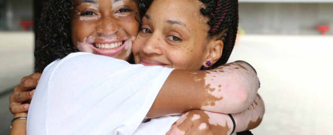 girl with Vitiligo poses hugging her mother