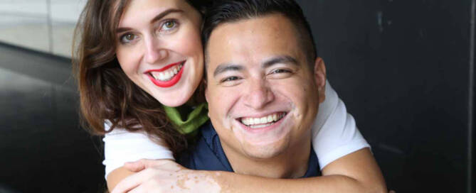 man and woman with Vitiligo hug and smile at the camera