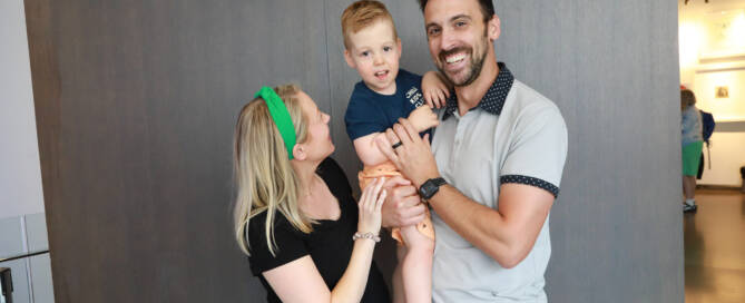 young boy with Phelan-McDermid Syndrome being held by his mother and father for photo