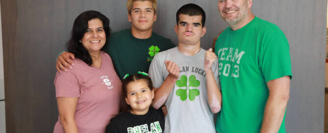 boy with Phelan-McDermid Syndrome poses for a photo with his sister, brother, mother, and father