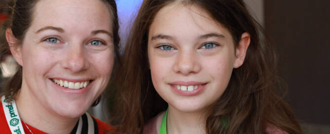 young girl with Phelan-McDermid Syndrome next to her mother. Both of them smiling at teh camera