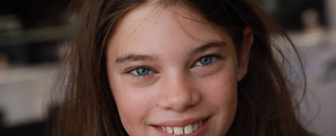 young girl with Phelan-McDermid Syndrome smiling at the camera, closeup photo