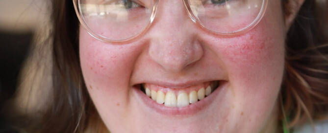 girl with Phelan-McDermid Syndrome wearing glasses and smiling at the camera