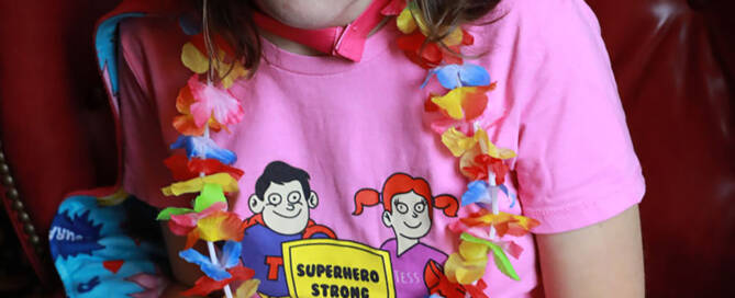 young woman wearing pink shirt and flower necklace sitting in red chair