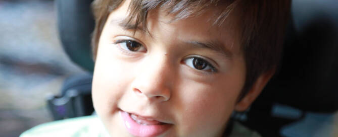 young boy with turquoise shirt looking into the camera, closeup photo