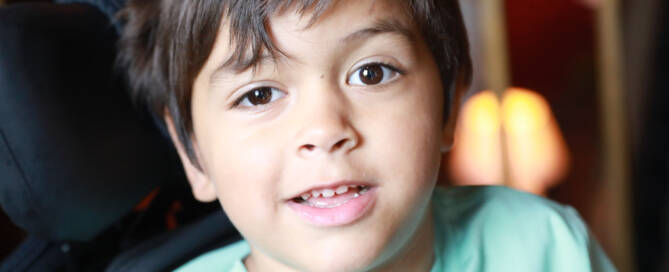 young boy with turquoise shirt looking into the camera, closeup photo