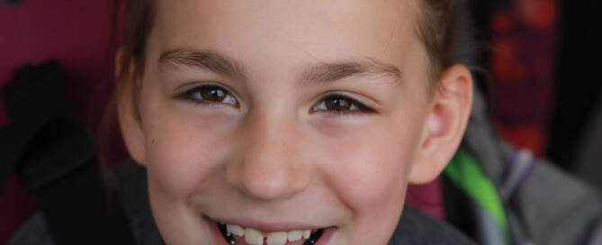 young girl with Phelan-McDermid Syndrome smiling into the camera, closeup photo