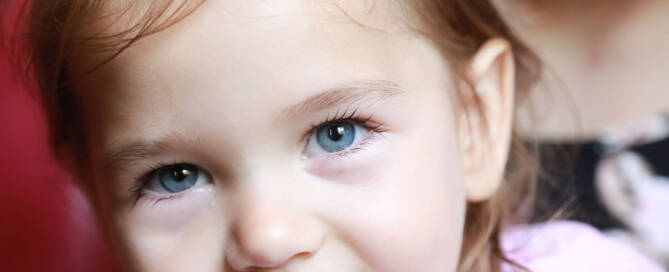 young girl wearing pink shirt smiling into the camera, closeup