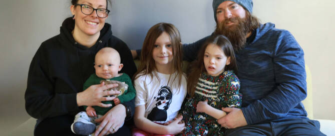 young girl with chromosome 5p- (Cri Du Chat) sitting on a couch with her family