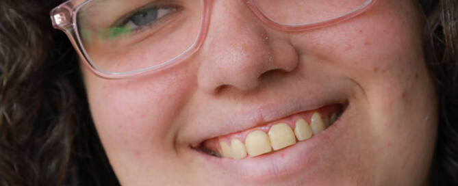 woman with Phelan-McDermid Syndrome wearing glasses smiling into the camera