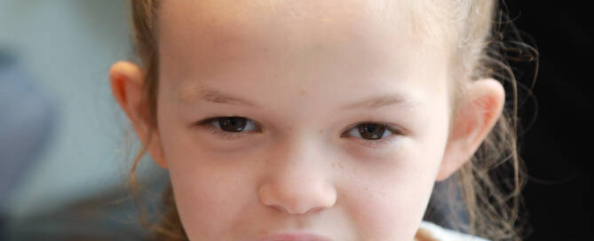 young girl with Phelan-McDermid Syndrome looks into the camera, closeup photo