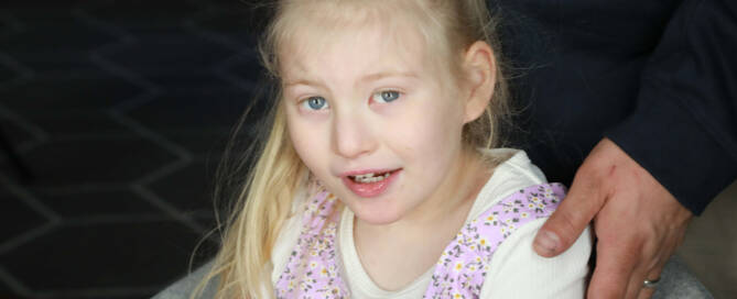 young girl with chromosome 5p- (Cri Du Chat) wearing pink dress and white boy looking into the camera, closeup photo