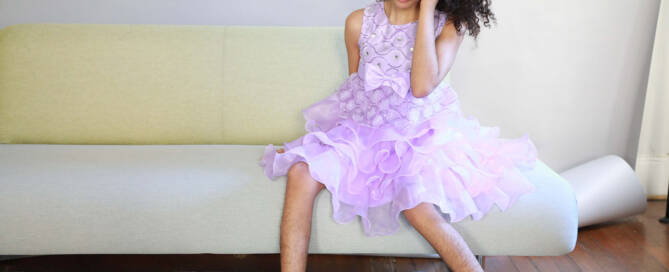 girl with chromosome 5p- (Cri Du Chat) wearing purple dress sitting on couch