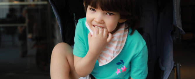 young girl with Phelan-McDermid Syndrome wearing turquoise shirt sitting in a stroller