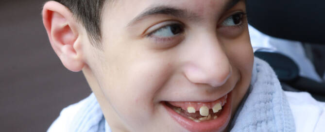 boy wearing white and smiling while looking to the right, closeup photo