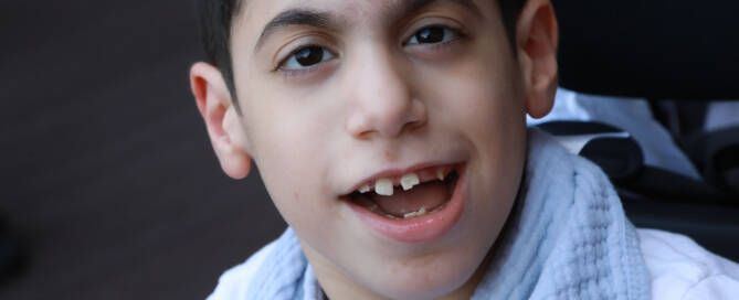 boy wearing white and smiling at the camera, closeup photo