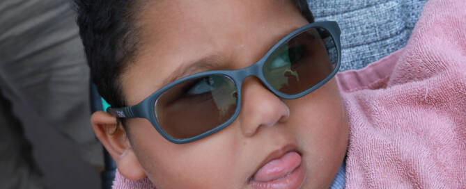 young girl with pink shirt and grey sunglasses looking to the right