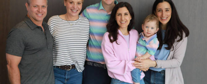 young boy with Phelan-McDermid Syndrome being held by his mother surrounded by extended family