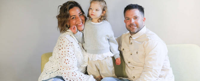 young girl with chromosome 5p- (Cri Du Chat) standing on couch while parents sit down next to her