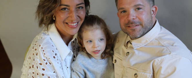 young girl with chromosome 5p- (Cri Du Chat) wearing grey shirt with her mother and father by her side