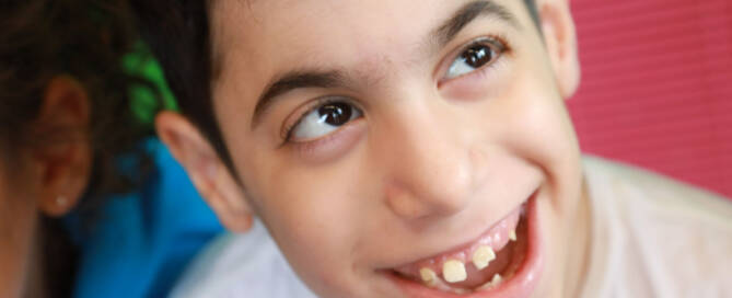 young boy wearing white shirt smiles while looking to the right, closeup photo