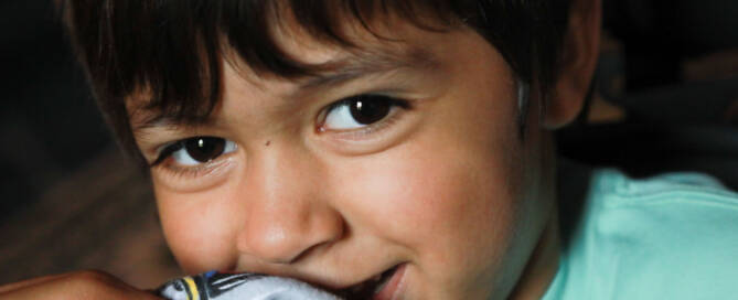 young boy with turquoise shirt smiling, closeup photo