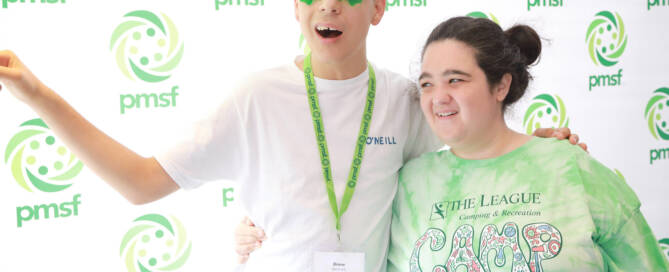 boy with Phelan-McDermid Syndrome wearing decorative green lens glasses hugging a girl