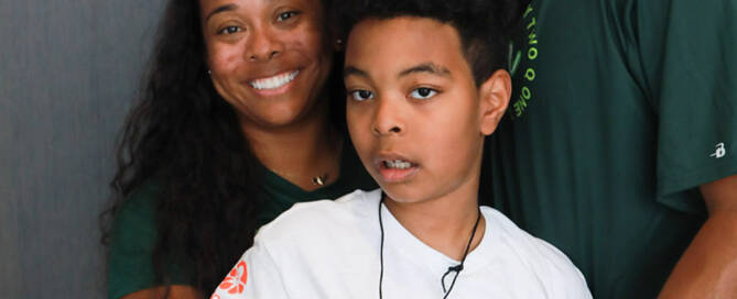 boy with Phelan-McDermid Syndrome poses with his mother and father for a photo