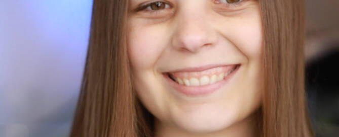 girl with Phelan-McDermid Syndrome wearing black shirt looking at the camera and smiling