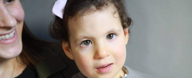 young girl with chromosome 5p- (Cri Du Chat) wearing grey shirt and pink boy looking into the camera