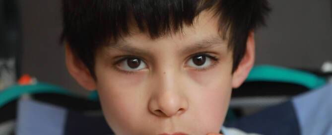 boy with Phelan-McDermid Syndrome looks deeply into the camera, closeup photo