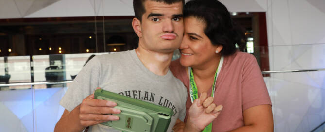 boy with Phelan-McDermid Syndrome wearing grey shirt stands loving with his mother