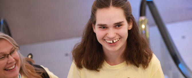 girl with Phelan-McDermid Syndrome wearing yellow shirt and coming up an escalator