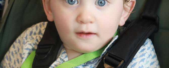 young boy with Phelan-McDermid Syndrome in a stroller looking into the camera