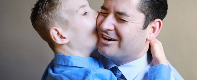 young boy with chromosome 5p- (Cri Du Chat) hugging his father and giving him a kiss