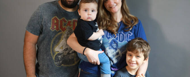 toddler boy with xxy syndrome being held by mother. family photo with father and brother as well