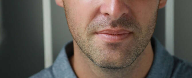 man with xxy syndrome wearing grey buttom up shirt looking at the camera, close up