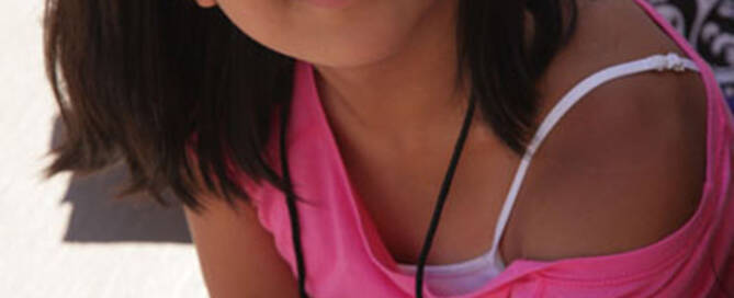 girl with turner syndrome wearing glasses and pink shirt smiling at the camera