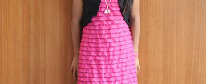 young girl with turner syndrome wearing pink dress smiling at the camera