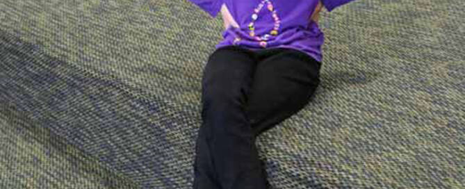 young girl with Xeroderma Pigmentosum wearing purple and sitting down at trampoline park