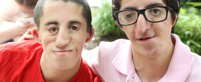 two young men with miller syndrome looking into the camera and smiling